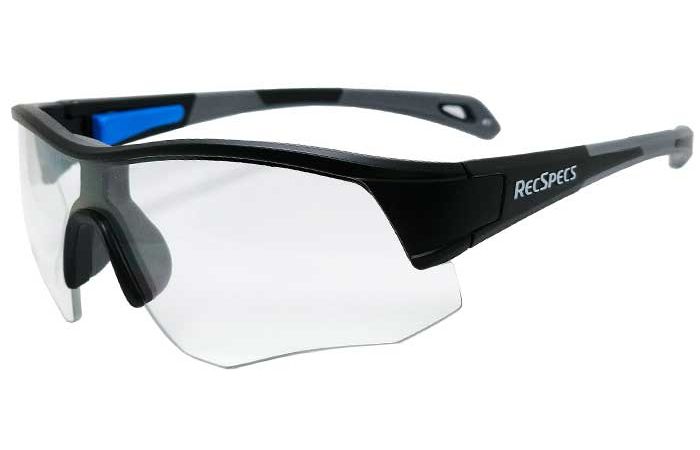 A pair of RecSpecs - Contact with shatterproof lenses and the brand name "RecSpecs" printed on the side. The glasses have a wrap-around design, a prominent nose bridge, and a partially rimless frame, meeting high impact standards for optimal protection.