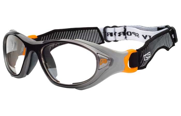 A pair of protective sports goggles with a black and gray frame, clear lenses, and an adjustable strap. The RecSpecs Helmet Spex XL features a black and white design, with lenses encased in a robust, wrap-around frame meeting impact resistance standards, complete with orange accents on the temples.